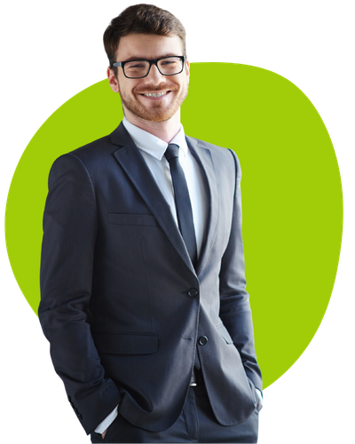 A confident man in a dark suit and tie, wearing glasses, stands with his hands in his pockets and smiles. Behind him is a vibrant green background that adds contrast to his formal attire.